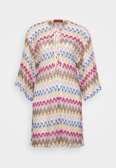 Färgglad stickad tunika med ett zigzag-mönster i nyanser av blått, rosa, gult och brunt. Har en rund halsringning och trekvartslånga ärmar.