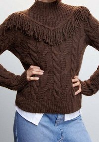 Pull marron en tricot avec un col montant et des détails à franges sur les épaules, présentant un motif tricoté en câble texturé et des poignets côtelés.