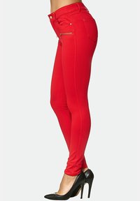 Röda slim fit-jeans med en slät textur, med hög midja, sidogylftor och framfickor, i kombination med svarta högklackade skor.