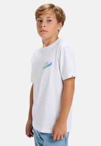 Bílý bavlněný tričko s krátkými rukávy a kulatým výstřihem. Na přední části se nachází multicolor grafika a na rukávu je logo nášivka.