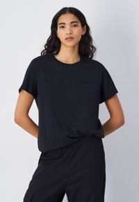 Sort bomulds t-shirt med rund hals og korte ærmer. Har broderet "Champion" logo over brystet i en mat finish.
