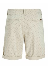 Short beige avec un petit motif losange foncé, ourlets retroussés, passants pour ceinture et deux poches arrière passepoilées, dont une avec une petite étiquette logo marron.