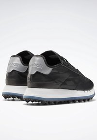 Baskets Reebok noires et grises avec semelles texturées et languettes argentées réfléchissantes au talon, vues de dos et en vue latérale inclinée.