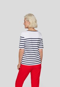 Short-sleeve striped top with navy and white horizontal lines, paired with red pants. Soft fabric and relaxed fit with a scoop neckline.