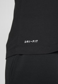 Schwarzes Dri-FIT Sport-T-Shirt mit glatter Textur, das ein weißes Logo nahe dem Saum und ein einfaches, rundes Ausschnittdesign aufweist.