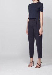 Námořnická košile s krátkým rukávem a vysokými, plisovanými kalhotami ve stejném námořnickém odstínu. Slim fit s jemným leskem, doplněné o černé sandály na vysokém podpatku.