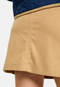 Top bleumarin matlasat, asortat cu o fustă maro deschis cu dungi. Fusta are tiv valurit și textură fină, evidențiind linii verticale distincte.