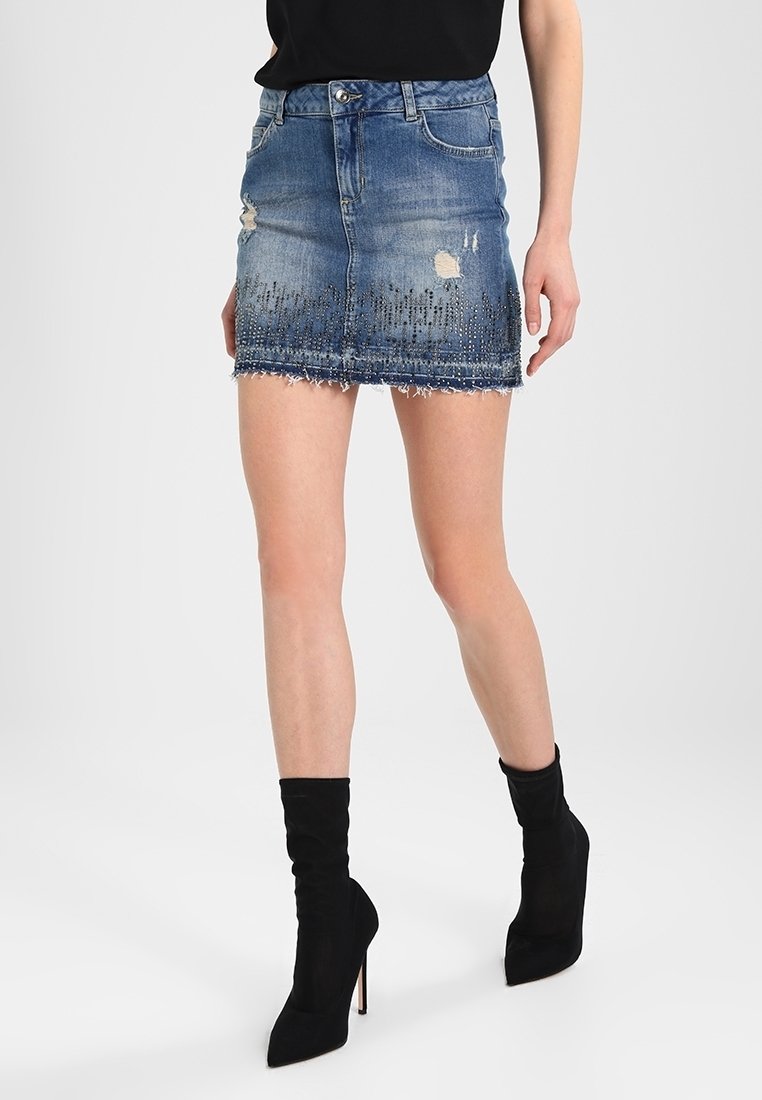 Jeansminikjol, ljusblå med slitna lappar, blekningar och fransar i nederkant. Har svarta dekorationer i nederkanten.