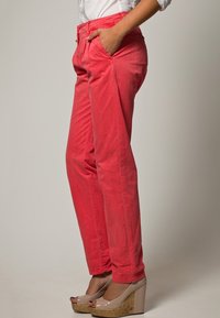 Röda bomullsshorts med avslappnad passform, två framfickor och lätt avsmalnande ben. Kombineras med ljusa kilklackar.