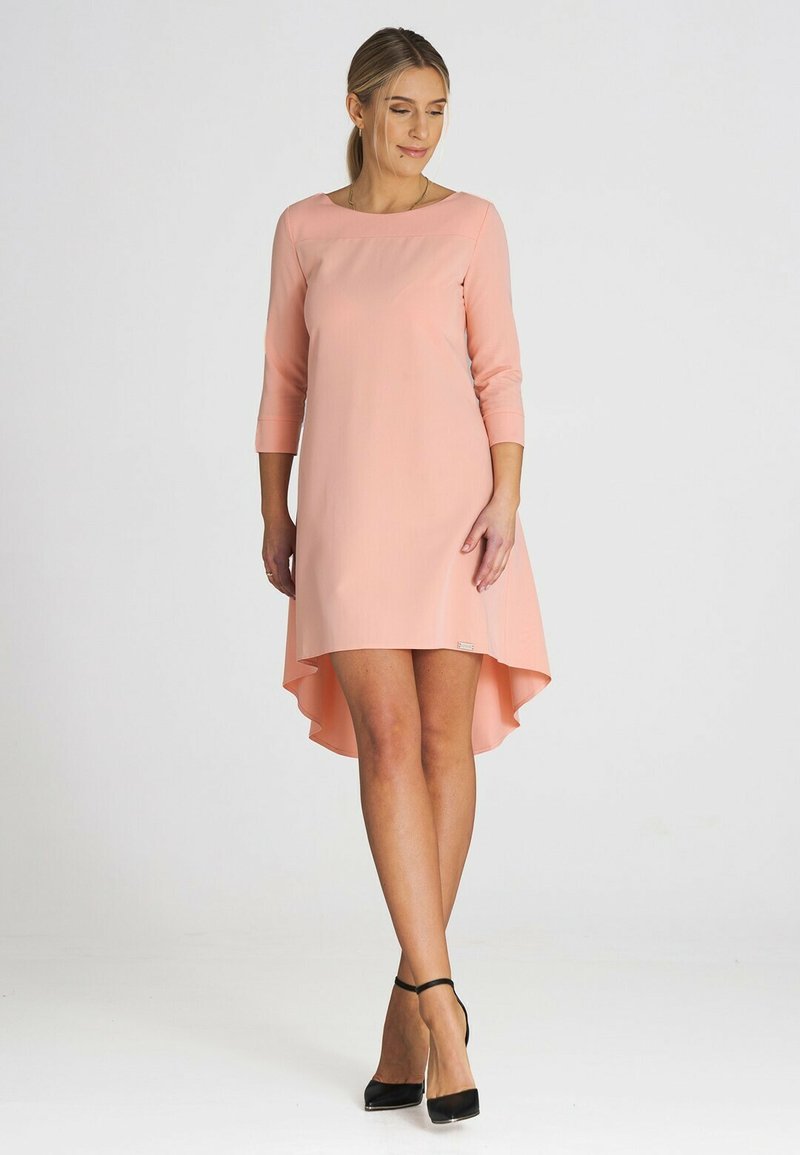 Rosa, knielanges Kleid mit Dreiviertelärmeln und asymmetrischem Saum. Hergestellt aus glattem Stoff, mit rundem Ausschnitt und minimalistischem Design.