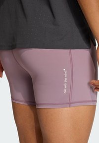 Μωβ αθλητικό σορτσάκι με ομαλή υφή, με λευκό τυπωμένο σύνθημα, εφαρμοστή γραμμή και λεπτομέρειες αντίθετων ραφών. Σκούρο ανθεκτικό στην αναπνοή τοπ από πάνω.