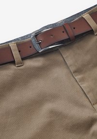 Bruine stoffen shorts met een gestructureerde oppervlakte, aangevuld met een bruine leren riem met een zilveren gesp en meerdere aanpassingsgaten.