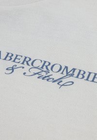 Λευκό βαμβακερό φούτερ με κεντημένο μπλε λογότυπο που γράφει "Abercrombie & Fitch" με καλλιγραφική γραμματοσειρά. Απλή υφή και σχέδιο.