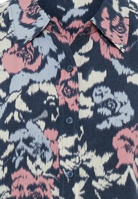 Blaues Hemd mit Blumenmuster, verziert mit rosa und grauen Akzenten. Mit einem Kragen und Knopfverschluss. Strukturierter Stoff.