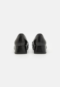 Black leather heeled shoes with a rounded toe and a mid-height block heel, featuring smooth textures and clean stitching details.