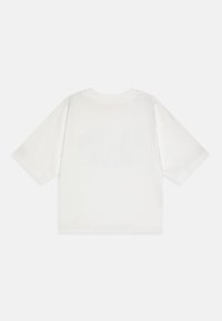 Camiseta blanca de manga corta hecha de algodón. Cuenta con un cuello redondo y un corte relajado. La parte trasera es lisa, sin logotipos ni diseños visibles.