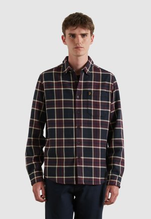 Geruit shirt in marineblauw, kastanjebruin en crèmewit, gemaakt van een textuurstof. Heeft een kraag, een voorzak en een knoopsluiting.