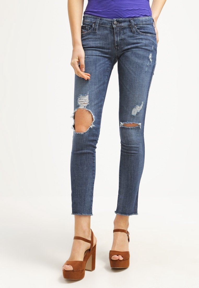Vaqueros de denim azul ajustados con desgastes en las rodillas y dobladillo deshilachado. Llevados con tacones de plataforma marrones para un contraste.