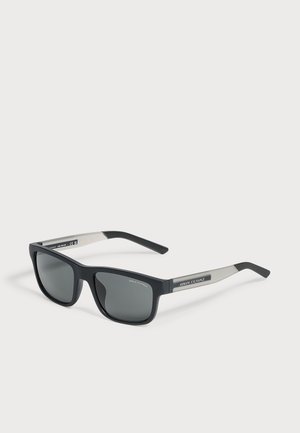 Schwarze und graue rechteckige Armani Exchange Sonnenbrille mit dunklen Gläsern auf weißem Hintergrund.