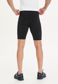 Zwarte sportieve shorts van stretchy materiaal, met een aansluitend ontwerp en twee zijzakken. Geaccentueerd met platte naden voor comfort.