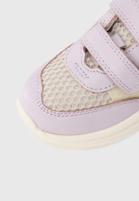 Κοντινό πλάνο  αθλητικού παιδικού παπουτσιού σε λιλά και μπεζ χρώμα με ύφασμα από δίχτυ και λουράκι βέλκρο σε λευκό φόντο.