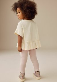 Top bianco a maniche corte con orlo arricciato, leggings rosa chiaro e stivaletti scintillanti con accenti viola. Morbido al tatto.