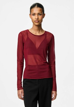 Top transparent bordeaux à manches longues avec une coupe ajustée et un col en V, superposé sur une couche de base unie. Présente un tissu léger avec une texture.