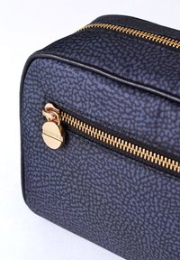 Black patterned cosmetic bag made of textured material with a gold zipper and hardware. Features a small flat zip pocket on the front.