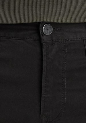 Sorte denim jeans med knaplukning, synlige stiching og en glat tekstur. En olivengrøn ribbet talje er også til stede.