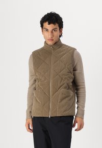 Gepolsterte Weste aus hellbraunem Cord mit hohem Kragen, einem Frontreißverschluss und zwei seitlichen Taschen. Strukturiertes Material mit Rautenmuster.