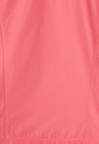 Camiseta deportiva de color coral claro, hecha de una tela suave; cuenta con una textura lisa, costuras planas y un diseño de dobladillo curvado y simple.