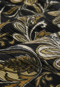 Tissu avec un fond noir présentant des motifs cachemire complexes en or, crème et brun foncé, mettant en valeur une texture lisse et un mouvement fluide.