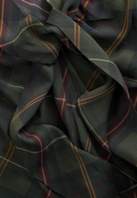 Tissu vert foncé avec une texture froissée présentant un motif à carreaux composé de lignes orange, crème et bordeaux.