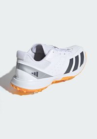 Scarpa sportiva bianca con strisce nere, dettagli grigi e suola arancione ad alta trazione. Presenta un design perforato e un sistema di allacciatura.