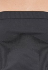 Tissu noir extensible avec des détails côtelés, présentant une texture lisse et un motif géométrique. Le bord supérieur comporte une large bande épaisse.