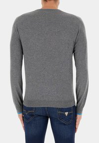 Maglione grigio a maniche lunghe con colletto rotondo, realizzato in un tessuto a maglia liscia. Presenta polsini e bordo a coste, e una silhouette aderente.