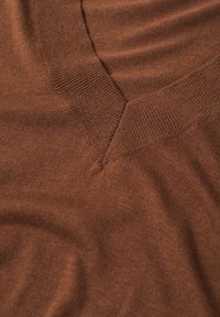 Pull en tricot marron avec un col en V, présentant une texture fine et douce ainsi que des détails côtelés le long du col et des bords.