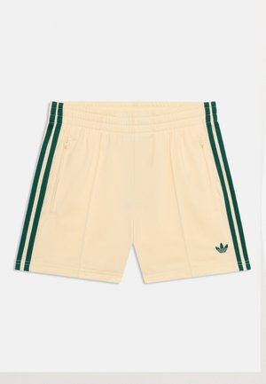 Krem šorc s tamnozelenim bočnim prugama, elastičnim pojasom, džepovima sa zatvaračem i malim Adidas logotipom na lijevoj nozi.