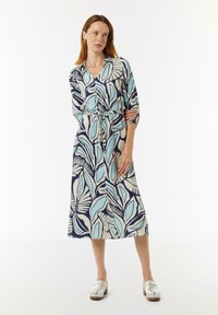 Bedrucktes Kleid mit dunkelblauem Hintergrund und großen hellblauen und cremefarbenen Blattmustern, tailliert mit einem Gürtel, mit Dreiviertelärmeln.