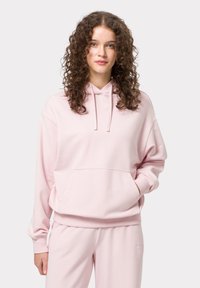 Růžová mikina s kapucí, přední kapsou, žebrovanými manžetami a lemem. Měkký materiál a volný střih, doplněná o odpovídající tepláky.
