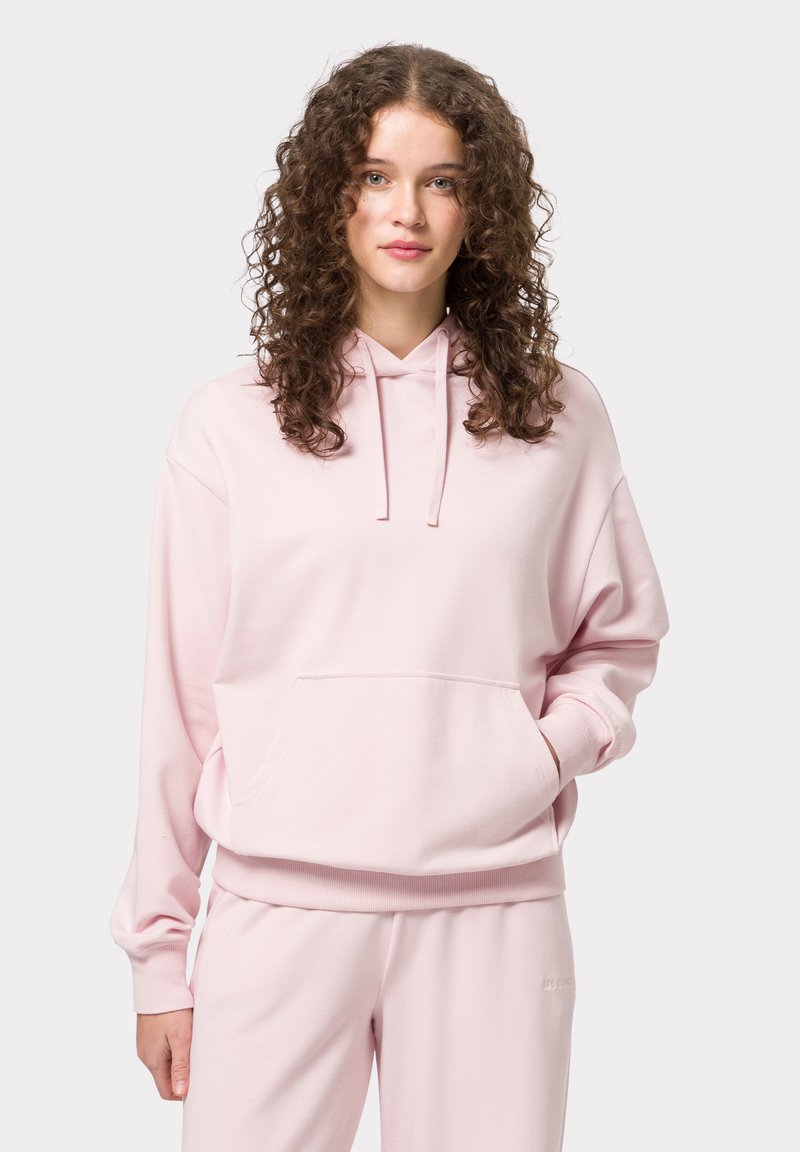 Růžová mikina s kapucí, přední kapsou, žebrovanými manžetami a lemem. Měkký materiál a volný střih, doplněná o odpovídající tepláky.