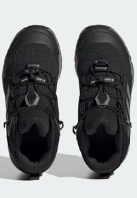 Czarne buty outdoorowe z teksturowaną cholewką, elastycznymi sznurówkami z systemem blokującym oraz wzmocnionymi czubkami dla zwiększonej trwałości.