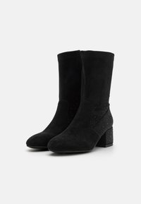 Bottes de cheville en cuir suédé noir avec un embout légèrement pointu, un talon carré texturé et des accents décoratifs en clous sur le panneau latéral.