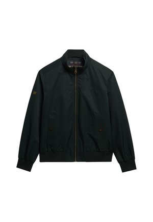 Chaqueta negra con cremallera y cuello alzado, puños elásticos y dos bolsillos frontales. Presenta un brillo sutil y un parche con marca en la manga.