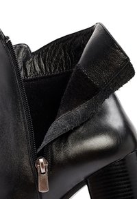 Stivale alla caviglia in pelle nera con zip e rivestimento in suede texture, dalla finitura liscia e un tacco alto e robusto.