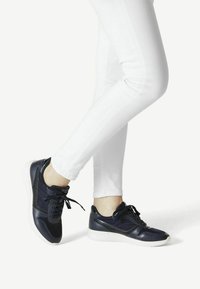 Marineblaue Ledersneaker mit weißen Gummisohlen, abgerundeter Spitze, gesteppten Akzenten und schwarzen Schnürsenkeln. Tragen Sie sie zu weißen Skinny Jeans.