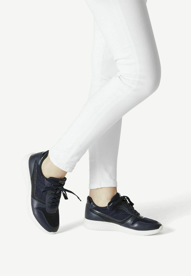 Marineblaue Ledersneaker mit weißen Gummisohlen, abgerundeter Spitze, gesteppten Akzenten und schwarzen Schnürsenkeln. Tragen Sie sie zu weißen Skinny Jeans.