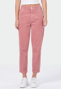 Roze corduroy pantalon met een rechte snit, voorzien van voorzakken, knoopsluiting en opgerolde broekspijpen. Draagt met witte sneakers.
