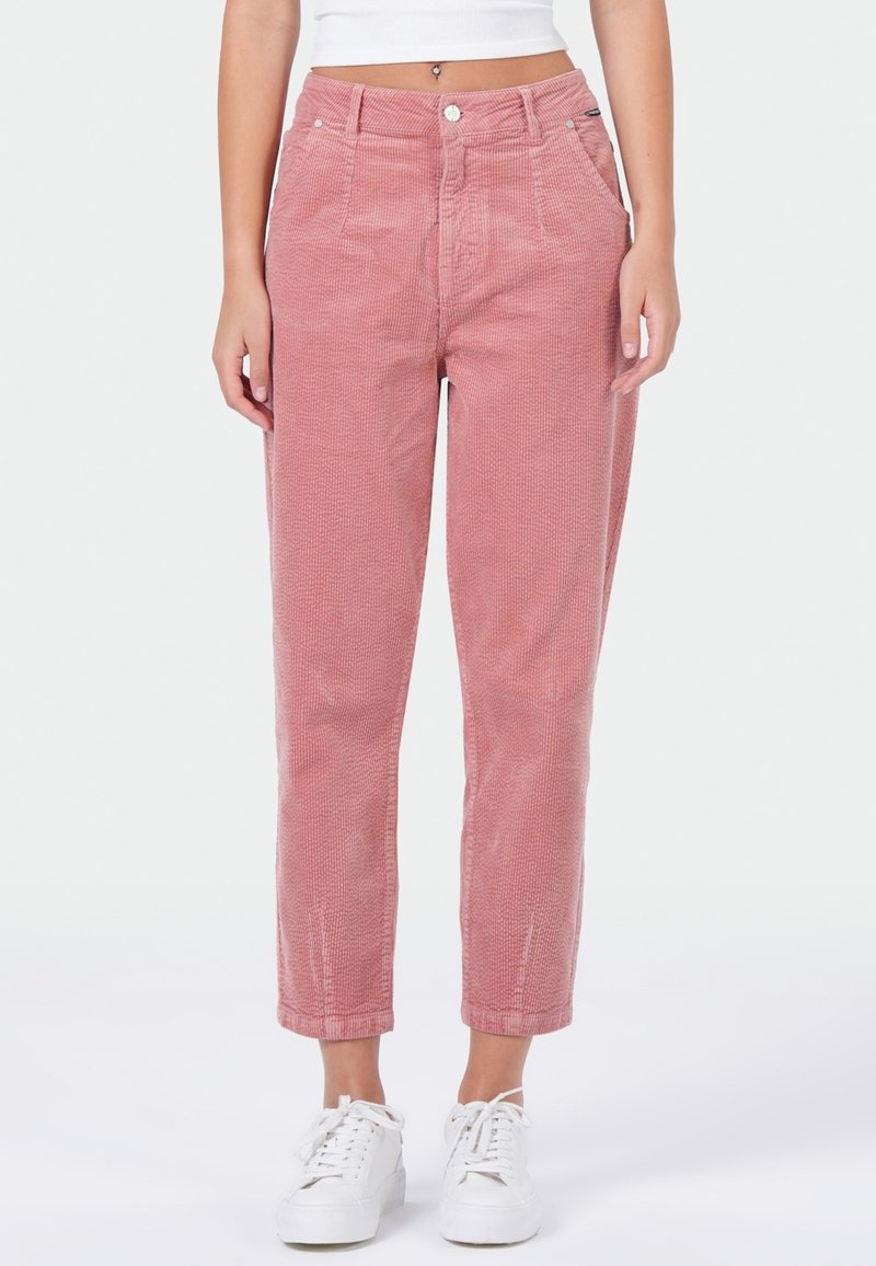 Roze corduroy pantalon met een rechte snit, voorzien van voorzakken, knoopsluiting en opgerolde broekspijpen. Draagt met witte sneakers.