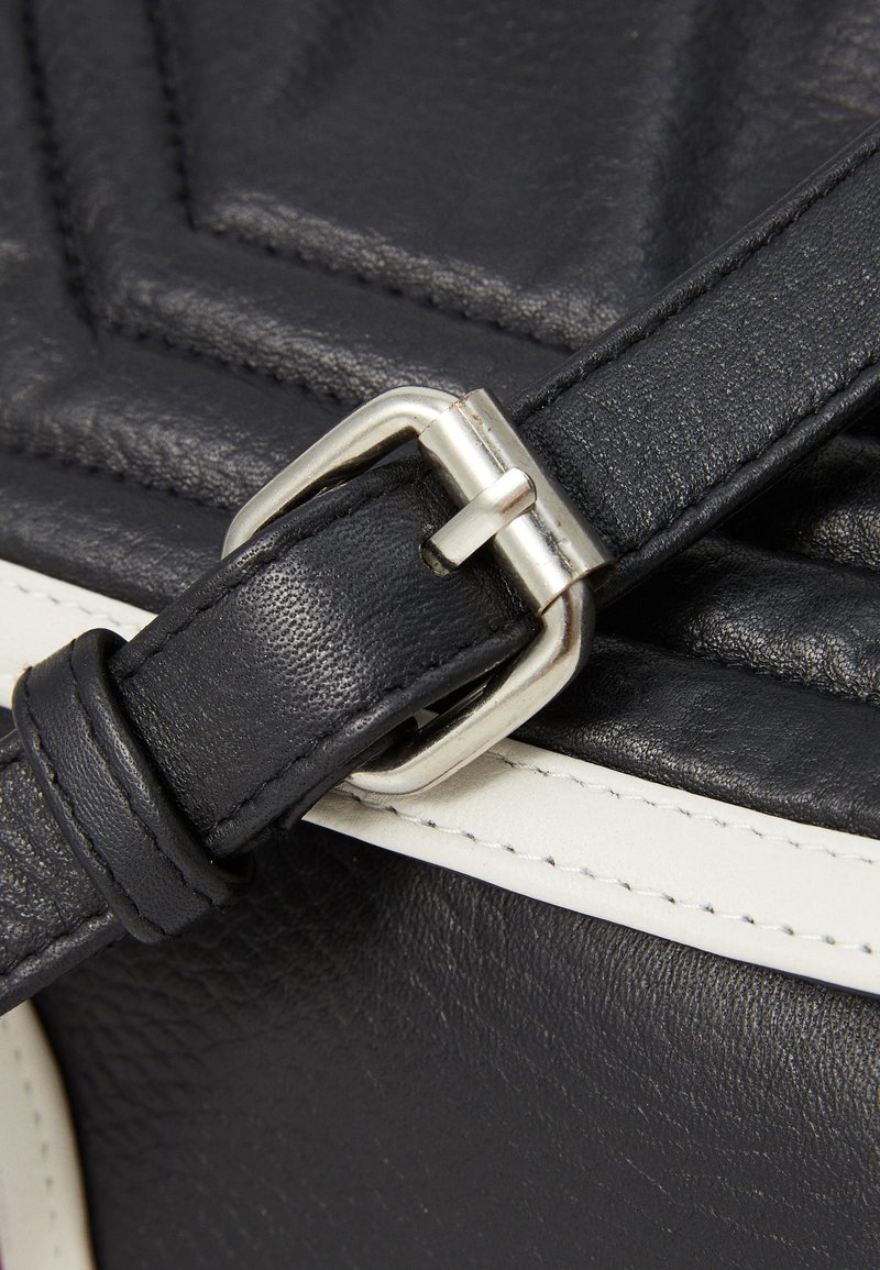Schwarze Lederhandtasche mit einem quilted Design, ausgestattet mit einer silberfarbenen Metallschnalle, schwarzem Tragegurt und kontrastierenden weißen Nähten.